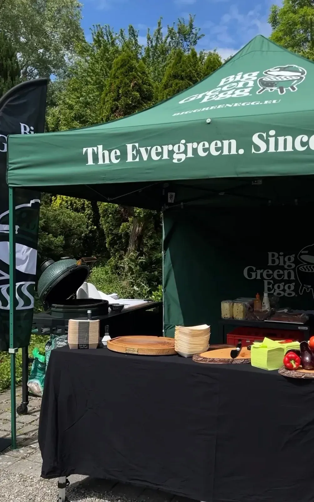 Event-Stand eines Big Green Egg Händlers: grünes Pavillonzelt, Keramikgrill und Präsentationstisch im Freien